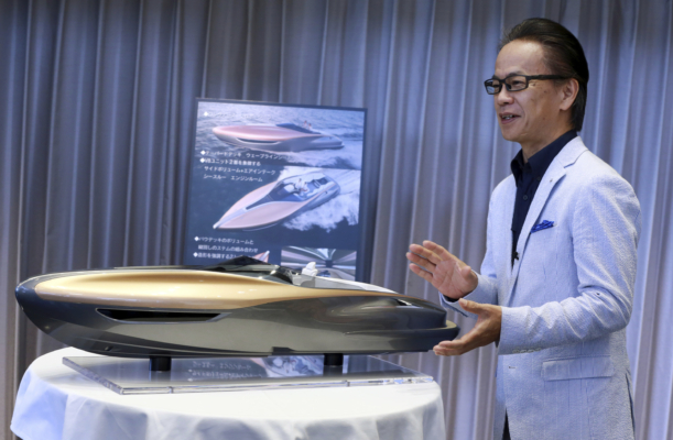 In this May 26, 2017, photo, Toyota's Senior Managing Officer Shigeki Tomoyama speaks next to a scale model of a Lexus luxury concept "yacht," in Tokyo. With a streamlined curvaceous design, inspired by a dolphin and as evocative of a Lexus car, it's being promised as a commercial product in the next few years. (AP Photo/Eugene Hoshiko)
