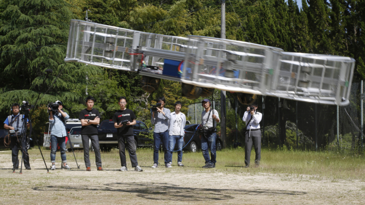 Tsubasa Nakamura, project leader of Cartivator, third from left, watches the flight of the test model of the flying car on a former school ground in Toyota, central Japan, Saturday, June 3, 2017 as another member, fourth from left, operates the remote control. (AP Photo/Koji Ueda)