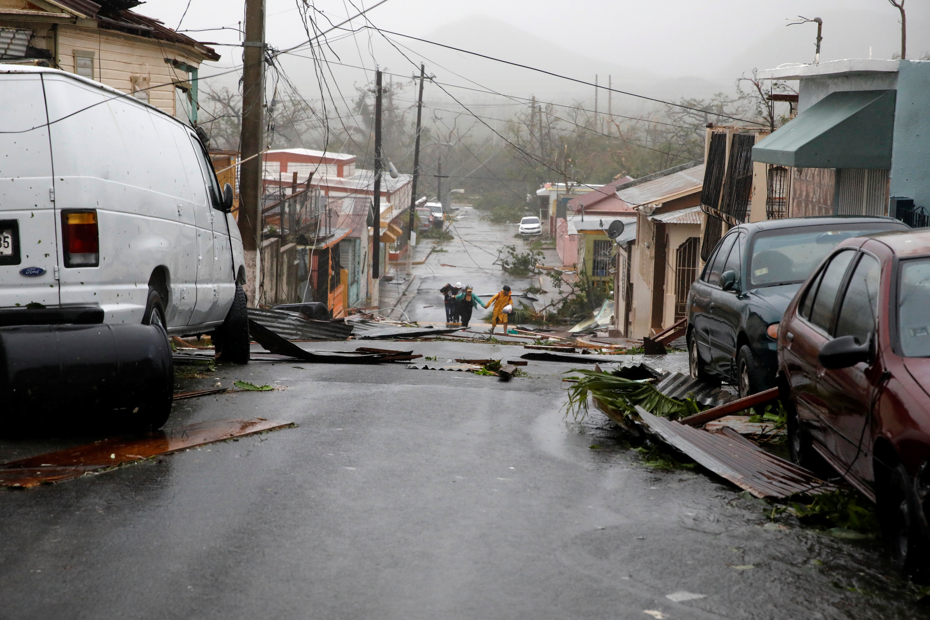 People walk on the street next to debris after the area was hit by Hurricane Maria in Guayama, Puerto Rico on Sept. 20, 2017. (REUTERS/Carlos Garcia Rawlins)