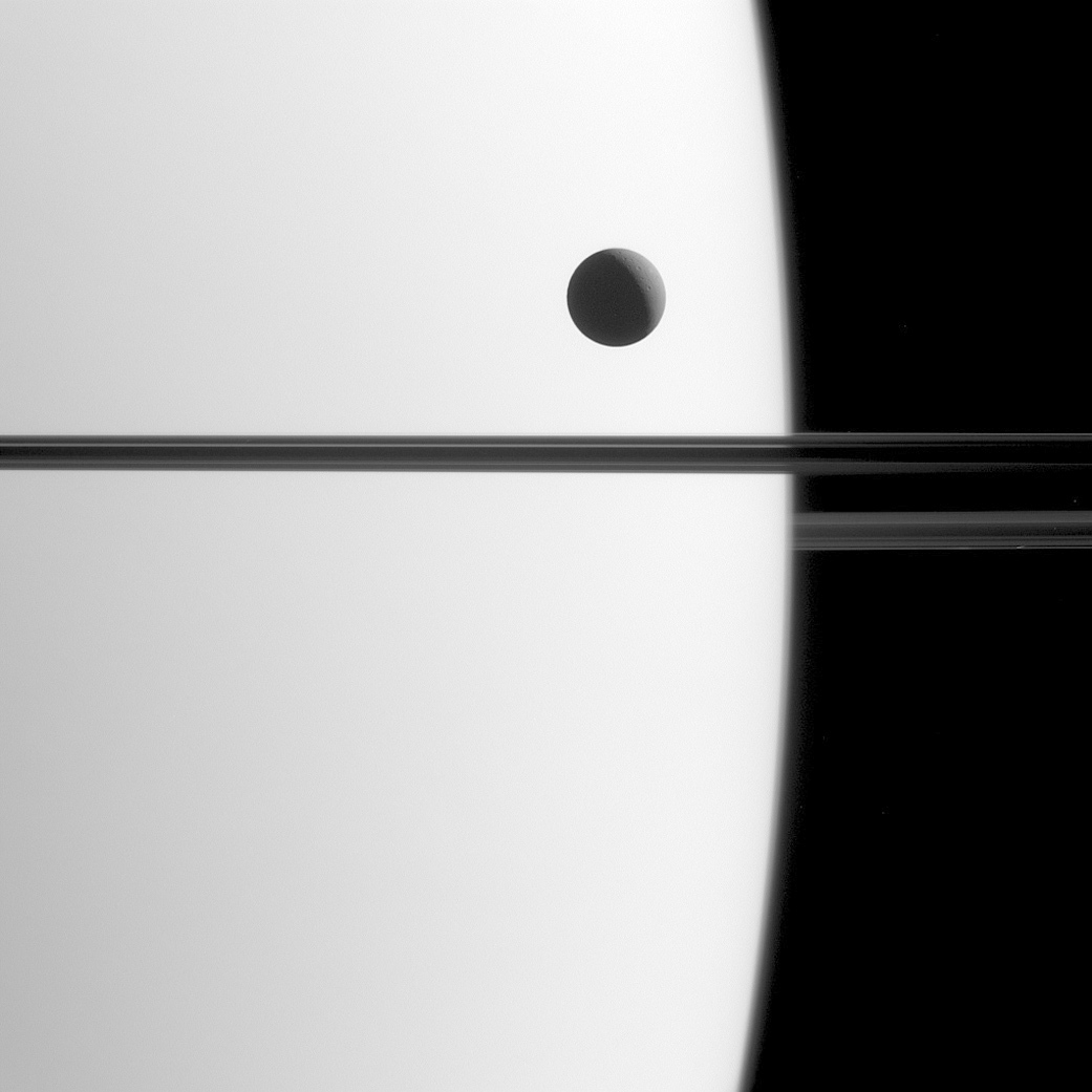 This May 21, 2015 image made available by NASA shows Saturn's moon Dione crossing the face of the gas giant, in a phenomenon astronomers call a transit. Transits play an important role in astronomy and can be used to study the orbits of planets and their atmospheres, both in our solar system and in others. (NASA/JPL-Caltech/Space Science Institute via AP)