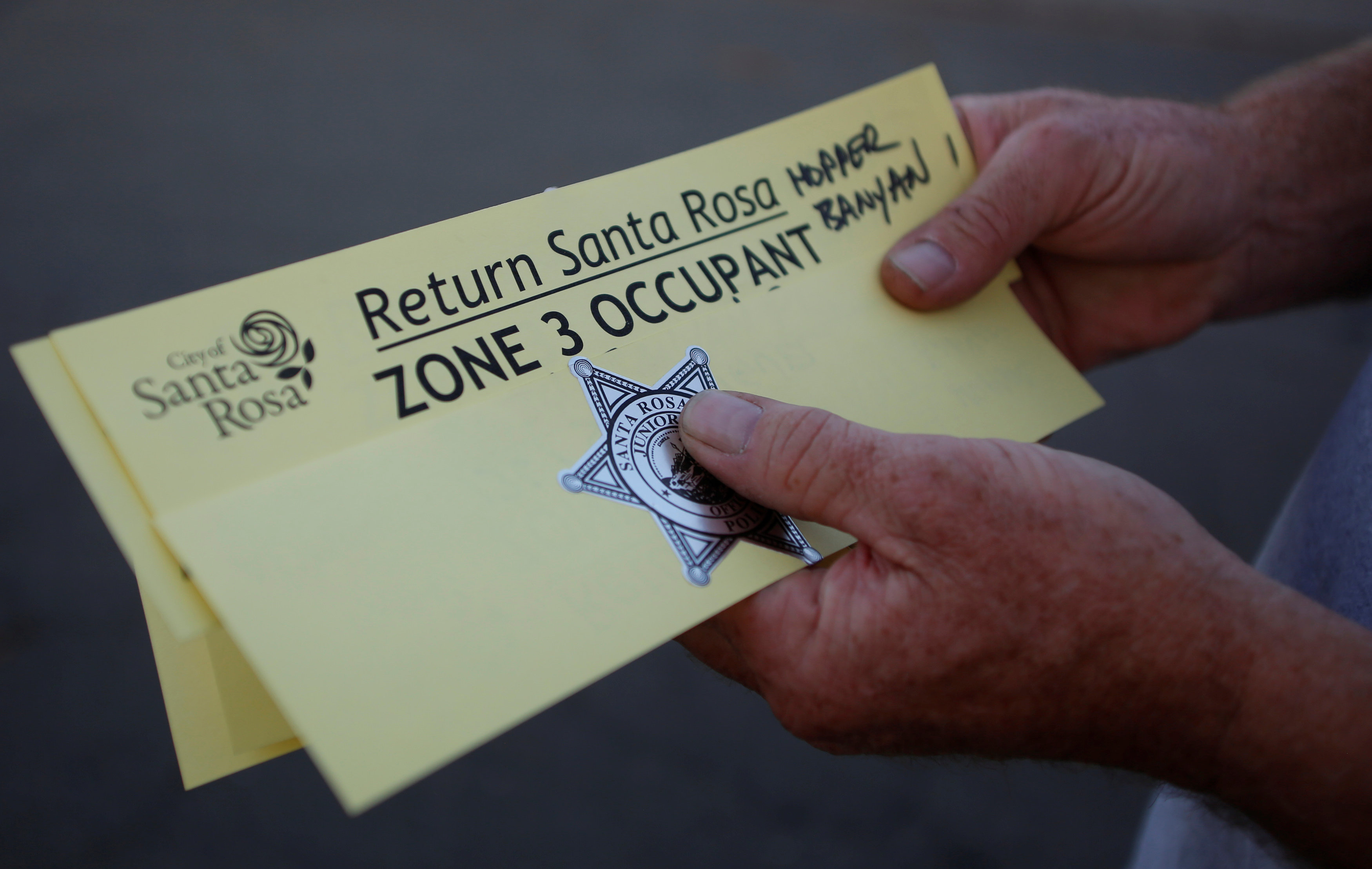 A man holds a pass from the Santa Rosa police department that allows him to come and go from the evacuation zone he lives in after a wildfire tore through adjacent streets in Santa Rosa, Calif., on Oct. 15, 2017. (REUTERS/Jim Urquhart)