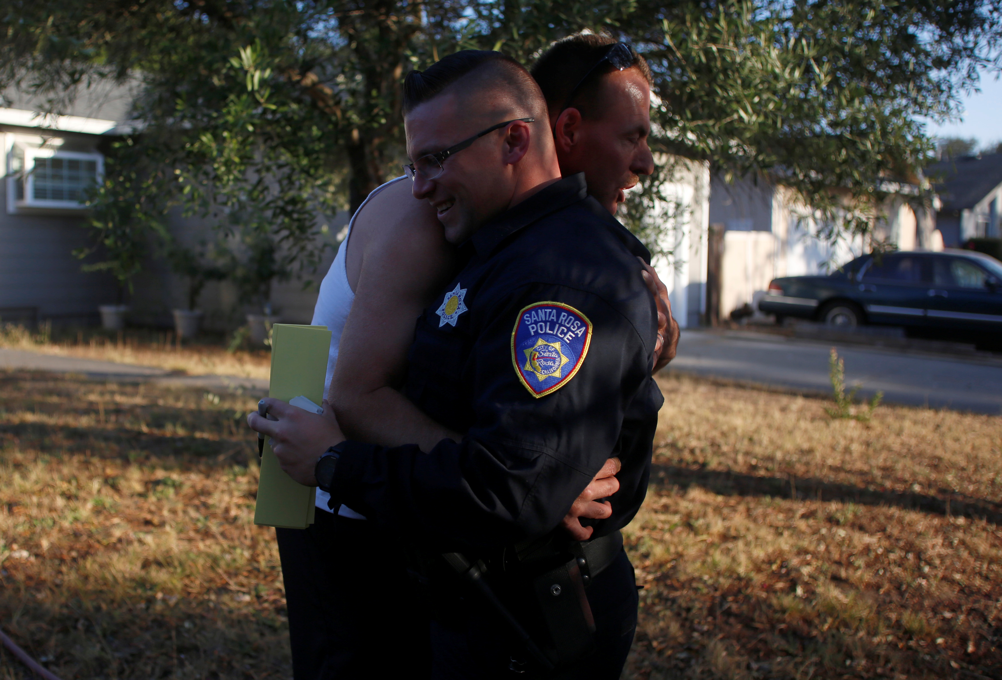 Calvin Sanders hugs Santa Rosa police officer Travis Dunn while receiving a pass that allows him to come and go from the evacuation zone he lives in after a wildfire tore through adjacent streets in Santa Rosa, Calif., on Oct. 15, 2017. (REUTERS/Jim Urquhart)
