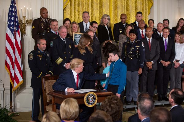 President Donald Trump, with two boys looking on, signs a declaration to declare the opioid crisis a nationwide public health emergency in the East Room of the White House in Washington on Oct. 26, 2017. (Samira Bouaou/The Epoch Times)