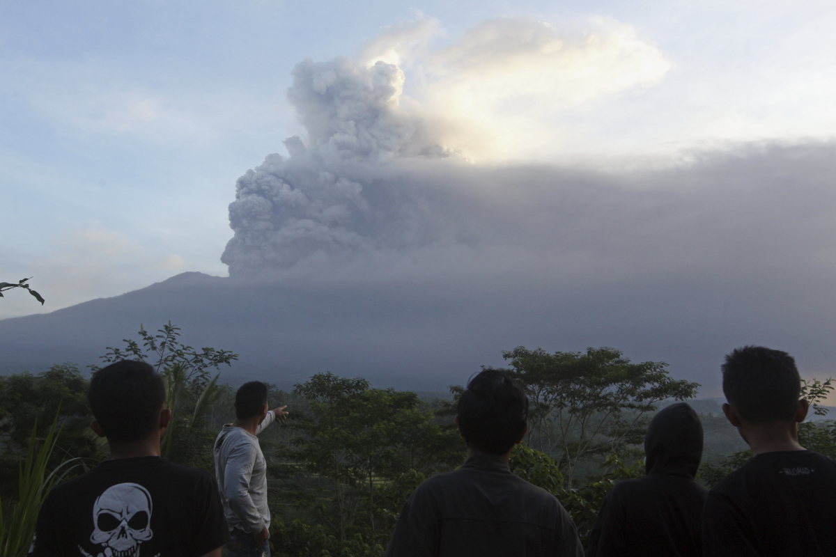 Villagers watch the Mount Agung volcano erupting during sunrise in Karangasem, Bali island, Indonesia on Nov. 26, 2017. (Firdia Lisnawati/AP)