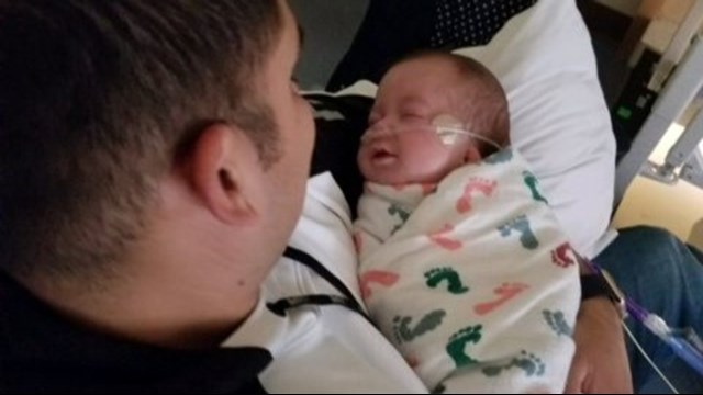 Officer Arturo Zepeda holds Axel Winch. (Aurora Police Department)
