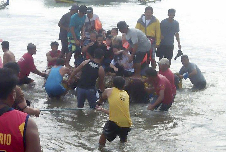 Volunteers pull a rubber boat with rescued passengers from the ill-fated M/V Mercraft 3 at Infanta township, Quezon province in northeastern Philippines Dec. 21, 2017. (AP Photo/DJ Kyle)