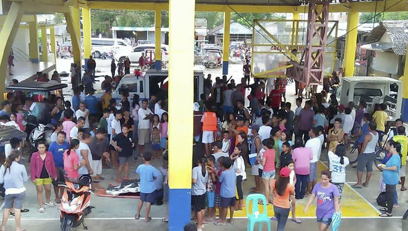 People gather at a multi-purpose building where rescued passengers from the ill-fated M/V Mercraft 3 were brought at Infanta township, Quezon province in northeastern Philippines Thursday, Dec. 21, 2017. The Philippine inter-island ferry with more than 250 passengers and crew, including Christmas holiday travelers, sank Thursday after being battered by fierce winds and big waves off the country's northeast, leaving at least four people dead and at least seven others missing, officials said. About 240 were pulled alive, some with injuries, from the rough sea by navy and coast guard personnel and a flotilla of fishing boats after the M/V Mercraft 3 sank in the Polillo Strait between Quezon province's Infanta town and the ferry's destination, Polillo island, officials said. (AP Photo/DJ Kyle)