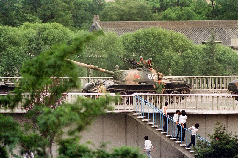 Chinese onlookers run away as a soldier threatens them with a gun on June 5, 1989 as tanks took position at Beijing's key intersections next to the diplomatic compound. (Catherine Henriette/AFP/Getty Images)