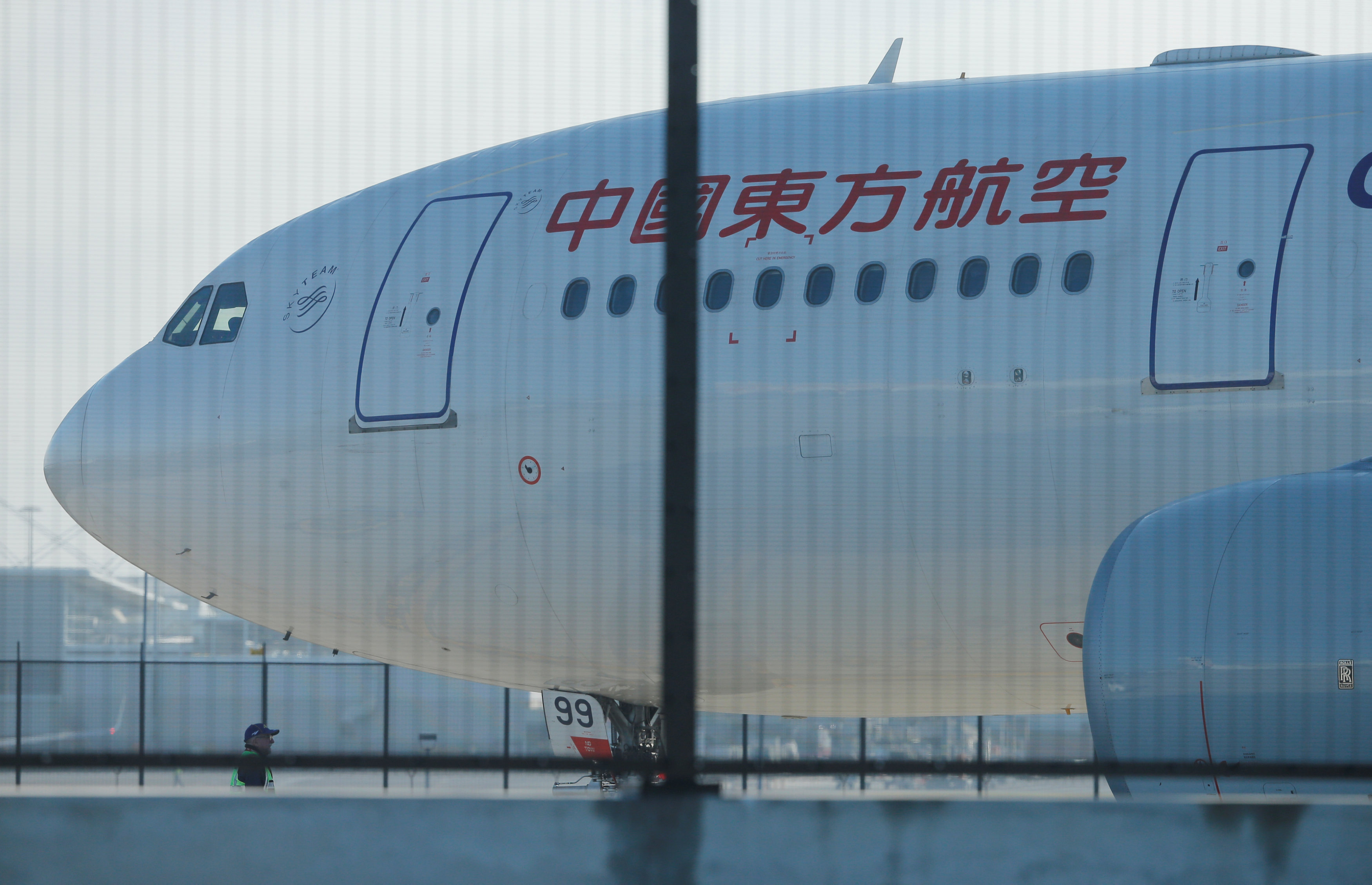 A man stands alongside the damaged engine of a China Eastern Airlines Airbus A330 aircraft on the tarmac at Sydney International Airport in Australia, June 12, 2017, after it made an emergency landing with a damaged engine. (Jason Reed/Reuters)