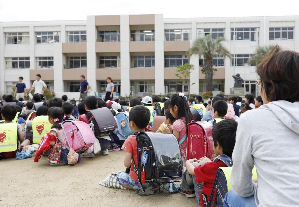Japanese students sit on a playground at Ikeda elementary school in Ikeda, Osaka prefecture, western Japan on June 18, 2018. (Kyodo/via Reuters)
