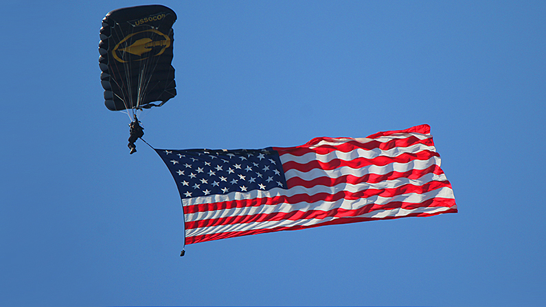A file photo of a member of the U.S. Army Jump Team displaying the flag while descending over Sebring International Speedway in Florida before a race. (Chris Jasurek/Epoch Times)