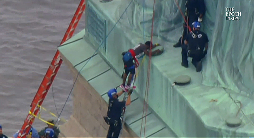 Emergency Service Unit officers assist Okoumou to a ladder whence she could climb down to the ground. (Screenshot/Fox News)
