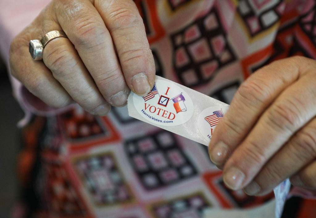 A woman in Texas hands out "I voted" stickers to voters at the Rummel Creek Elementary polling place in Houston on Nov. 6, 2018. (Loren Elliott/Getty Images)