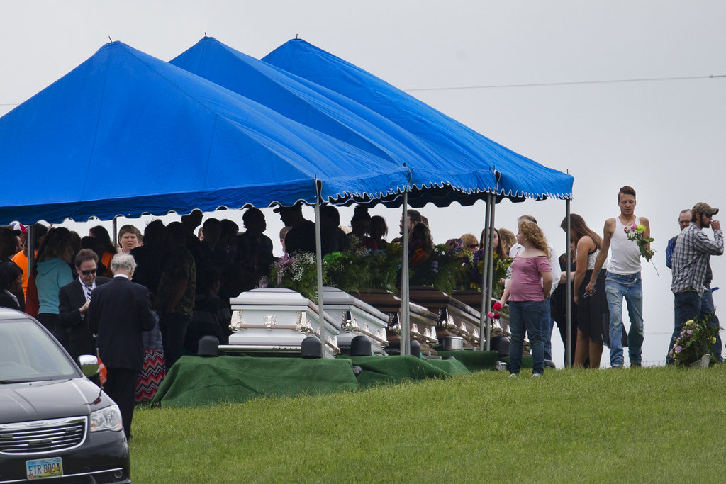 Mourners gather around caskets for six of the eight members of the Rhoden family found shot at four properties near Piketon, Ohio, on April 22, 2016, during funeral services at Scioto Burial Park in McDermott, Ohio, on May 3, 2016. (AP Photo/John Minchillo, File)