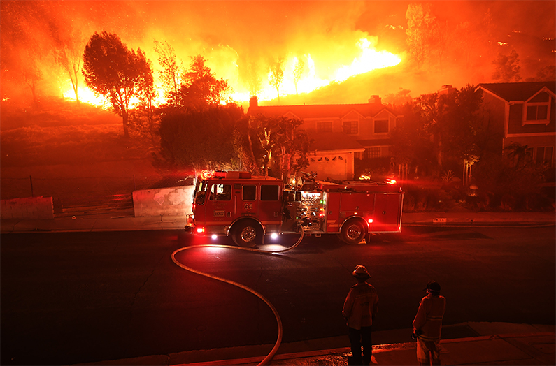 Los Angeles County firefighter looks on as the out of control Woolsey Fire explodes behind a house in the West Hills neighborhood on November 9, 2018. (Kevork Djansezian/Getty Images)