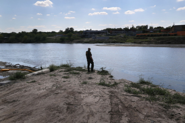 A U.S. Border Patrol agent looks into Mexico from the bank of the Rio Grande at the U.S.-Mexico border