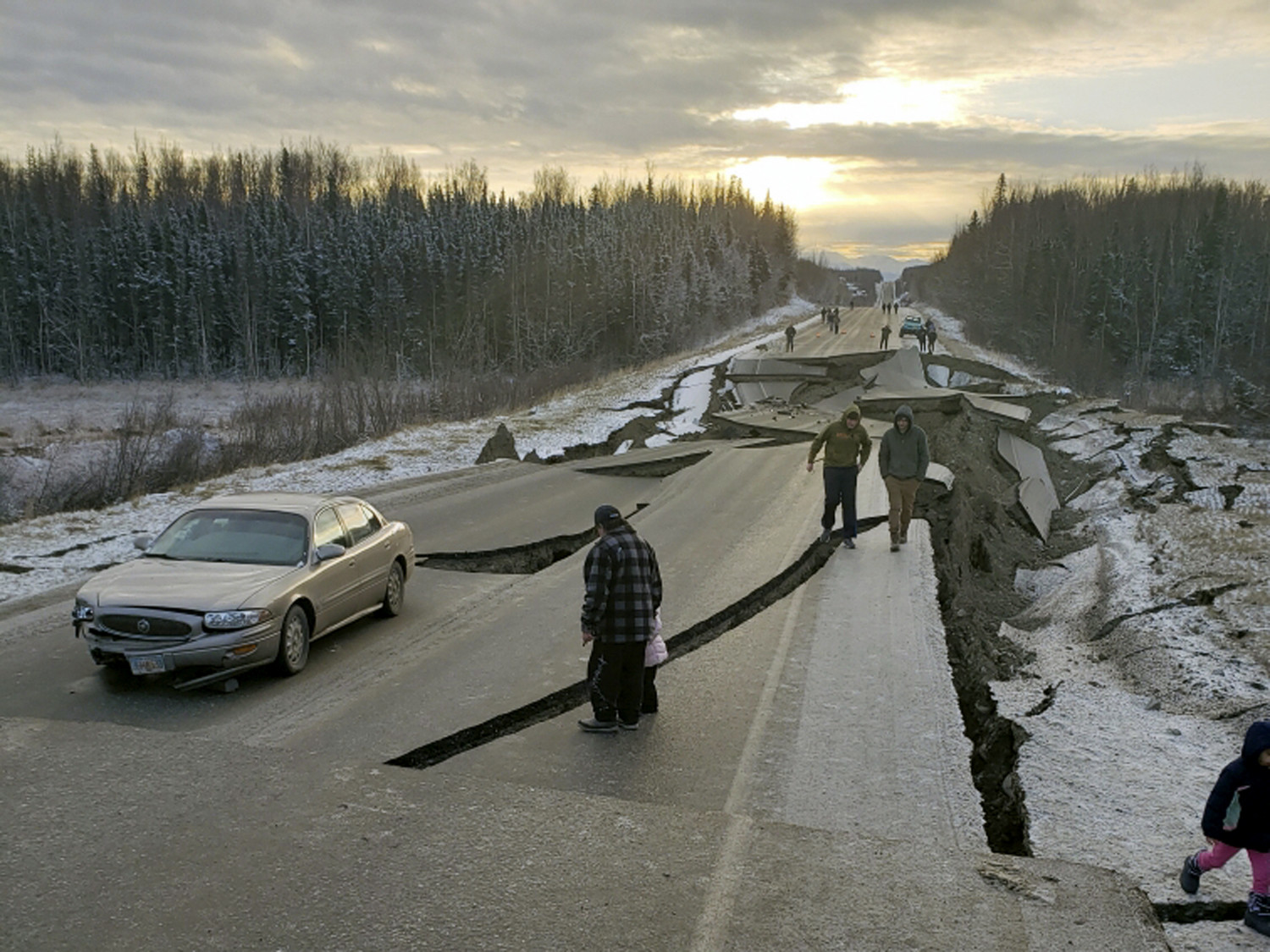 People walk along Vine Road in Wasilla, Alaska, after the 7.0 earthquake, Nov. 30, 2018, (Jonathan M. Lettow via AP)