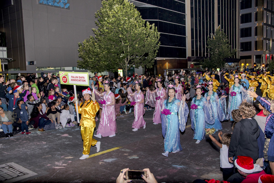 The Falun Gong community holds a sign as they walk through a parade in the annual Christmas Pageant in Perth, Australia, on Dec. 1, 2018. (Sam Lin/The Epoch Times)