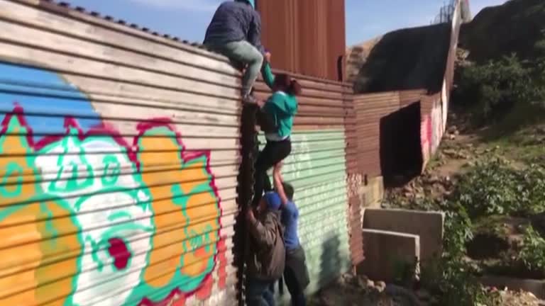 migrants climb fence in daylight