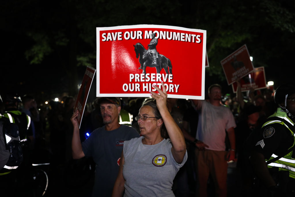 People supporting the Silent Sam statue receive a police escort through a shouting crowd to their vehicles after protesting where the statue stood before it was illegally removed, in Chapel Hill, N.C., on Aug. 30, 2018. (Logan Cyrus/AFP/Getty Images)