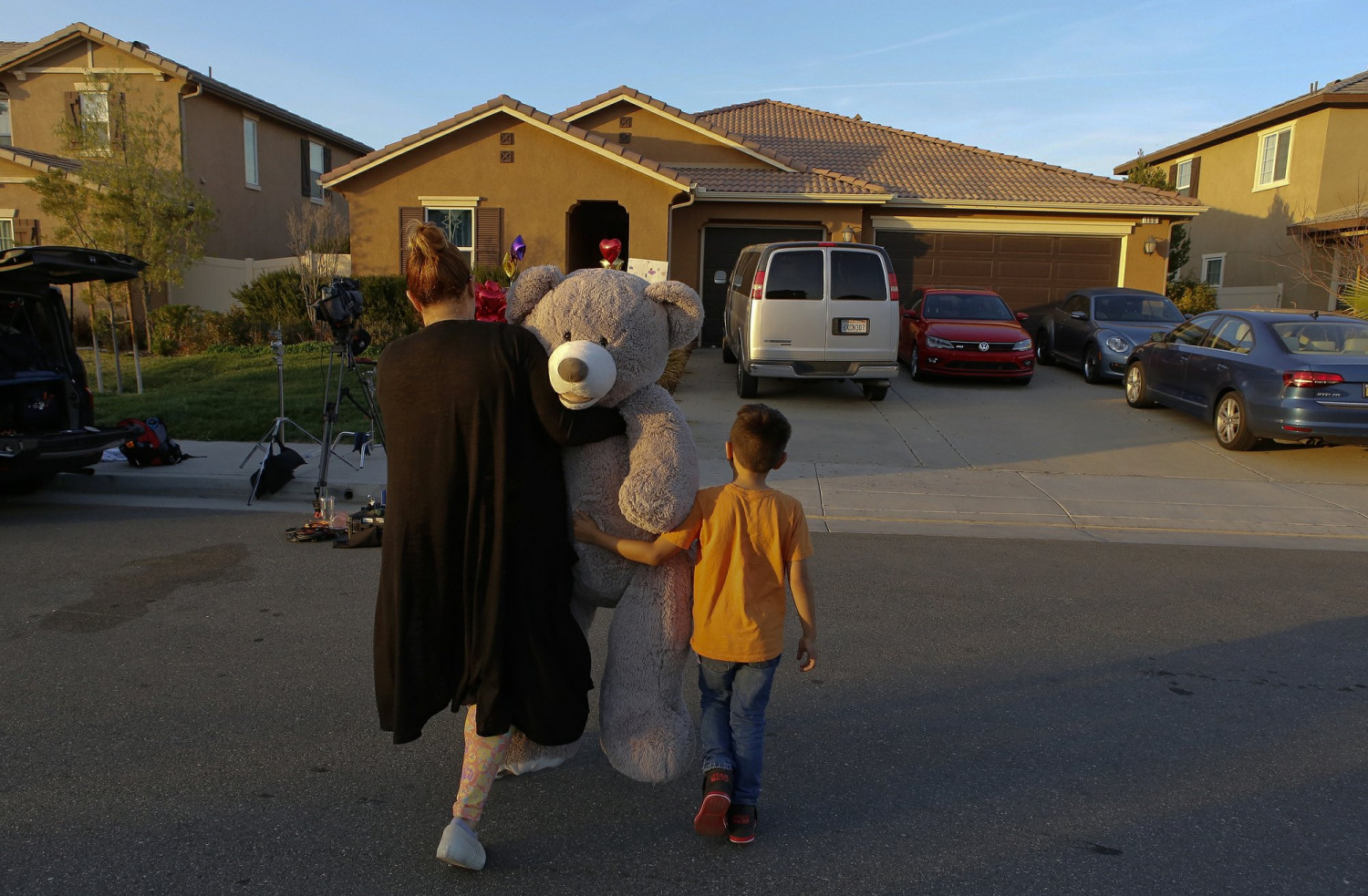 In this Jan. 18, 2018, file photo, neighbor Avery Sanchez walks with his mother, Liza Tozier, to drop off his large "Teddy" as a gift for the children who lived in a home where police arrested a couple on accused of holding 13 children captive in Perris, Calif. (AP Photo/Damian Dovarganes)