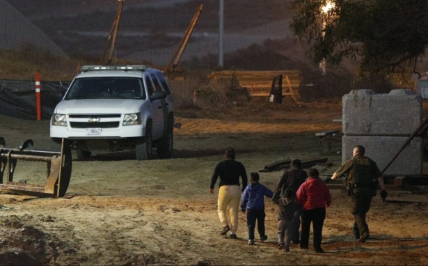 Illegal aliens are escorted by a U.S. Border Patrol agent as they are detained after climbing over the border wall from Playas de Tijuana, Mexico, to San Ysidro, Calif., on Dec. 3, 2018. (Rebecca Blackwell/AP Photo)