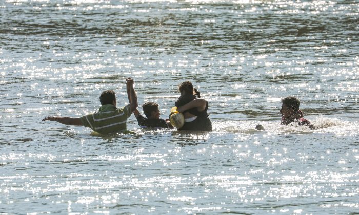 Illegal border crossers are rescued by agents on a U.S. Customs and Border Protection boat as they get stuck halfway across the Rio Grande from Mexico into Eagle Pass, Texas, on Feb. 16, 2019. (Charlotte Cuthbertson/The Epoch Times)