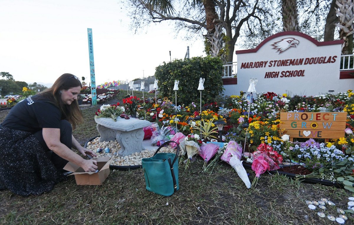 Suzanne Devine Clark, an art teacher at Deerfield Beach Elementary School, places painted stones at a memorial outside Marjory Stoneman Douglas High School during the one-year anniversary of the school shooting ,in Parkland, Fla., on Feb. 14, 2019. (Wilfredo Lee/AP Photo)