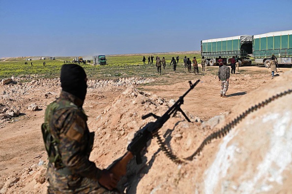 A Syrian Democratic Forces (SDF) fighter stands guard as Islamic State group's fighters and their families leave IS's last holdout of Baghouz in Syria's northern Deir Ezzor province on Feb.20, 2019. (Photo by BULENT KILIC/AFP/Getty Images)