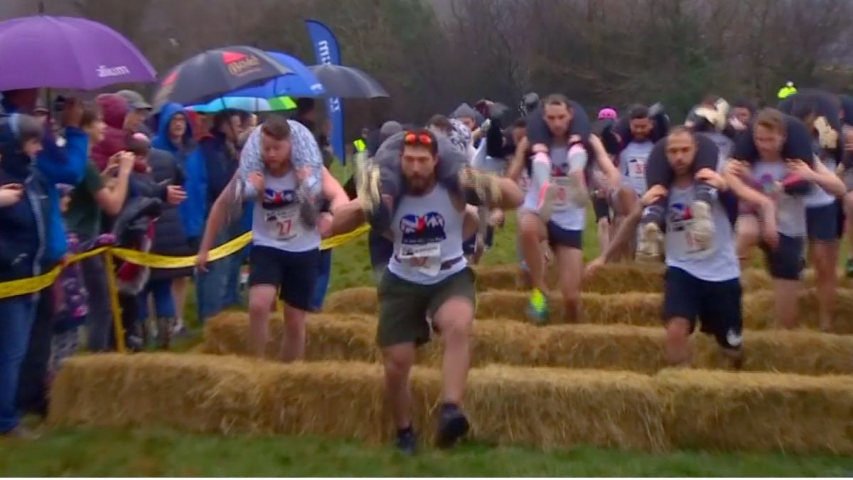 Runners jumping over short stacks of hay during Britain's annual 'Wife Carrying Championship' race in Dorking, UK, on March 3, 2019. (Screenshot/Reuters)