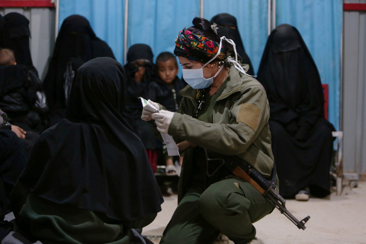 A soldier of Syrian Democratic Forces (SDF) checks documents of a wife of ISIS terrorist at a clinic at al-Hol displacement camp in Hasaka governorate, Syria, on April 2, 2019. (Ali Hashisho/Reuters)