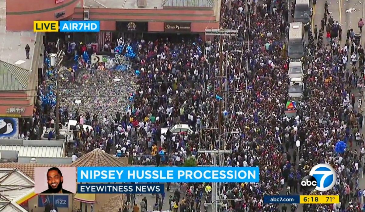 Thousands of people around the memorial and shrine where rapper Nipsey Hussle was shot and killed, as a hearse carrying his body drives by in South Los Angeles on April 11, 2019. (ABC7 via AP)