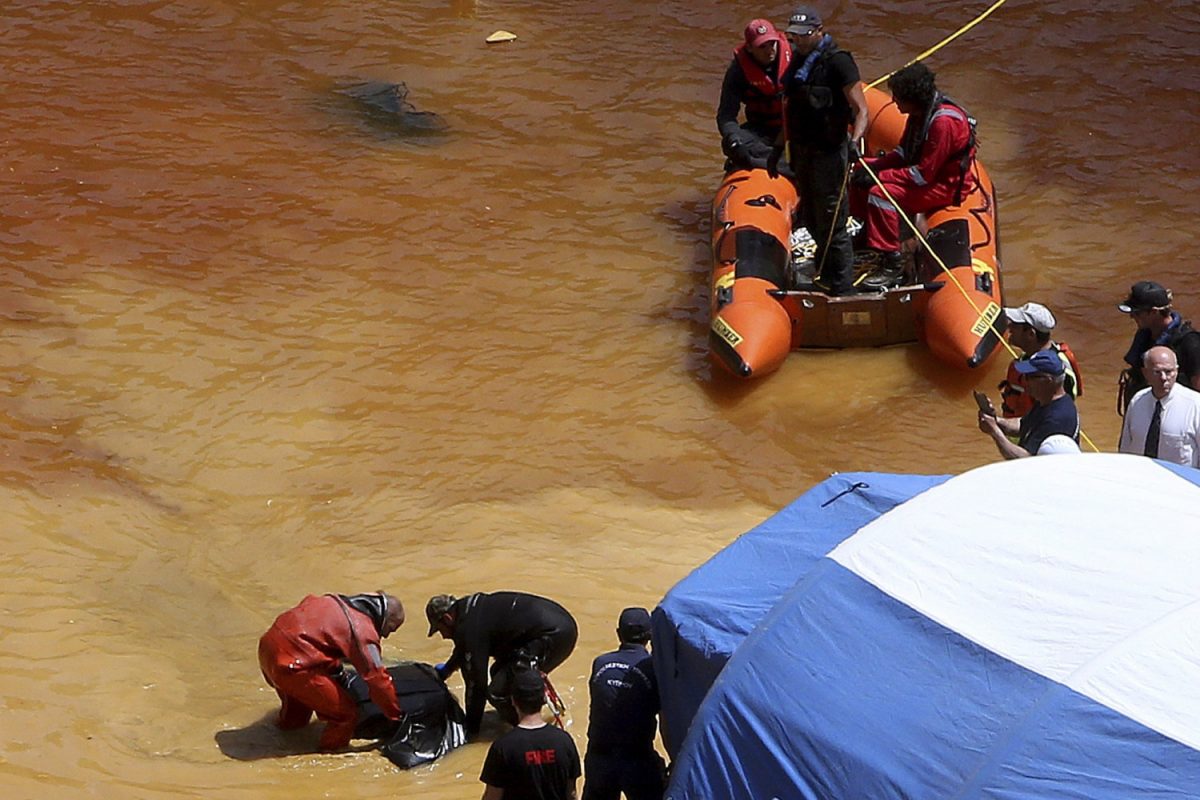 A diver (L) and an Investigator hold a suitcase found in a man-made lake, near the village of Mitsero outside of the capital Nicosia, Cyprus on April 28, 2019. (Petros Karadjias/Photo via AP)