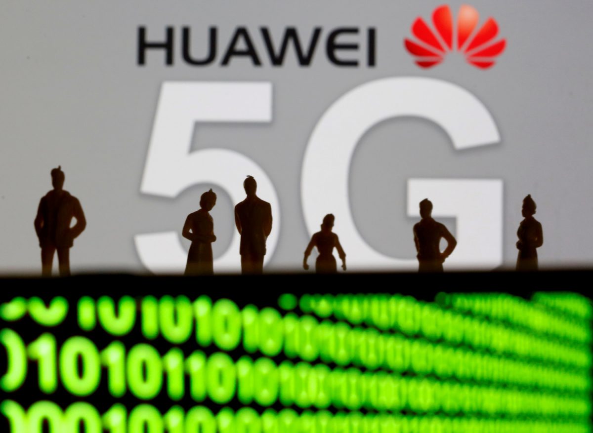 Small toy figures are seen in front of a displayed Huawei and 5G network logo in this illustration picture