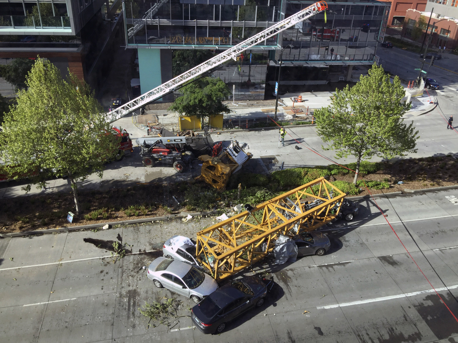 Firefighters and police officers work to clear the scene where a construction crane fell from a building on Google's new Seattle campus crashing down onto one of the city's busiest streets and killing multiple people on April 27, 2019. (AP Photo/Frank Kuin)