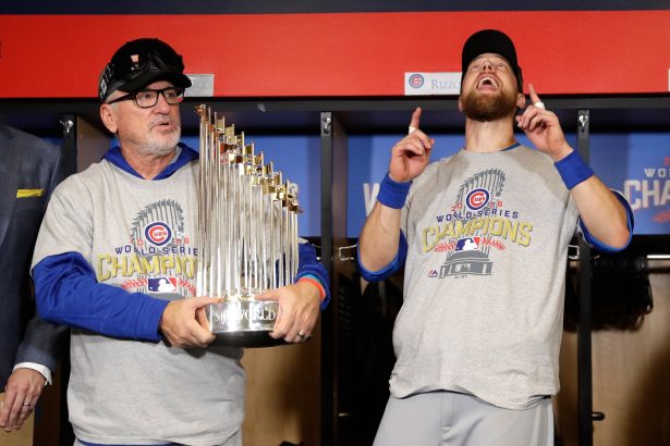 Manager Joe Maddon of the Chicago Cubs poses with The Commissioner's Trophy as Ben Zobrist #18 reacts after the Chicago Cubs defeated the Cleveland Indians 8-7 in Game Seven of the 2016 World Series in Cleveland, Ohio, on Nov. 2, 2016. (David J. Phillip-Pool/Getty Images)