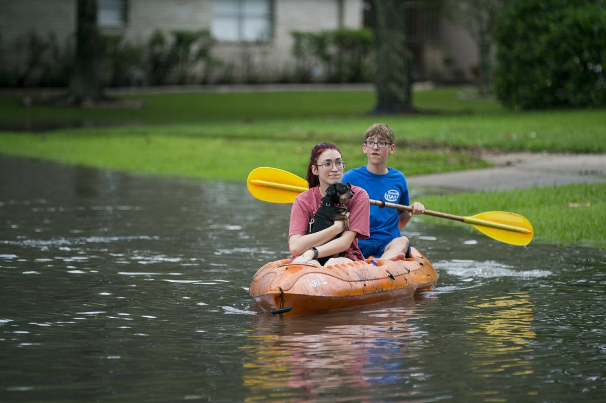 Siblings Katie and Lander Meinen survey their street by kayak with their dog, Bailey, in the Colony Bend neighborhood of Sugar Land, Texas, on May 8, 2019. (Mark Mulligan/Houston Chronicle via AP)