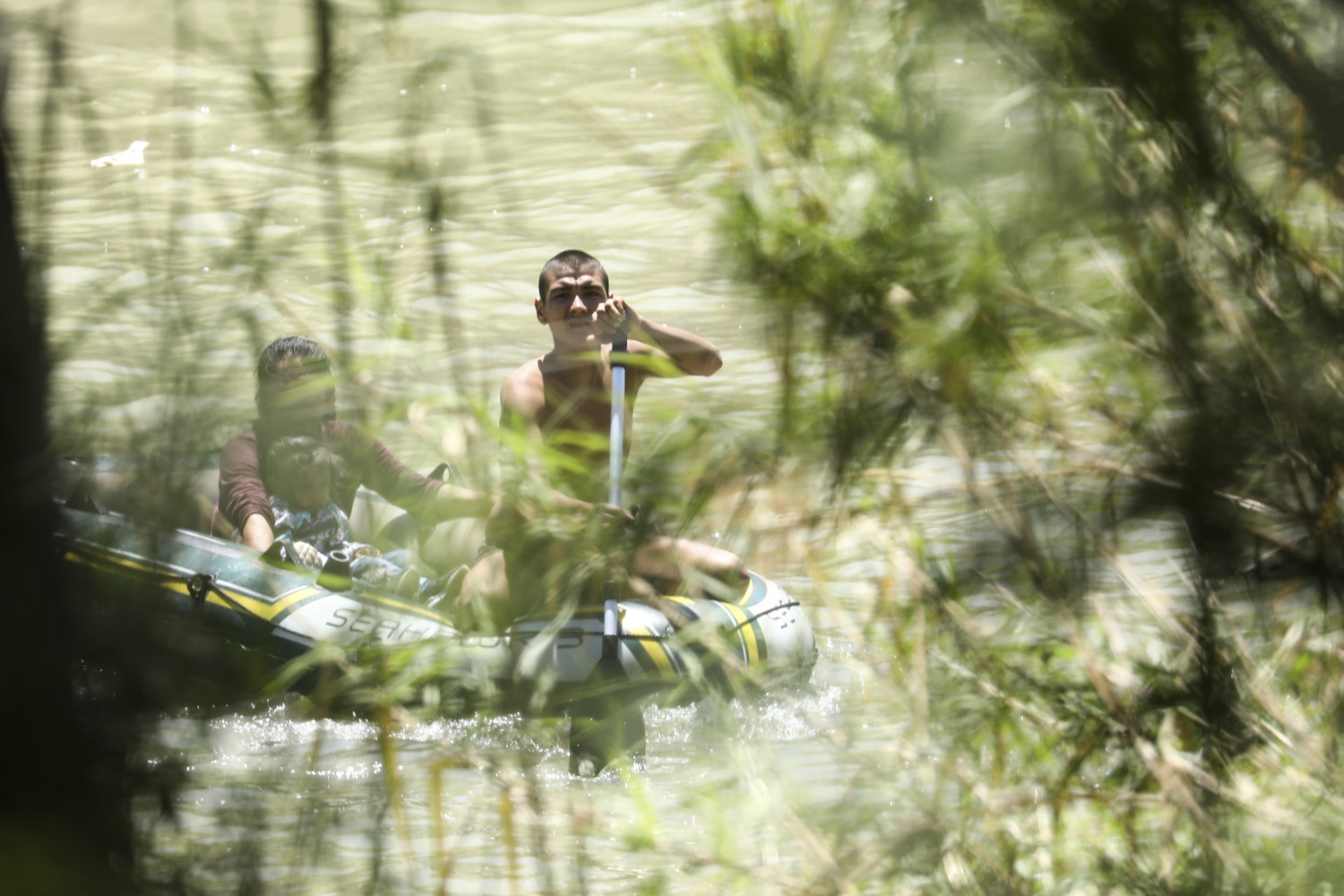 A smuggler ferries a Guatemalan woman and her daughter across the Rio Grande on a raft from Mexico to the the United States near McAllen, Texas, on April 18, 2019. (Charlotte Cuthbertson/The Epoch Times)