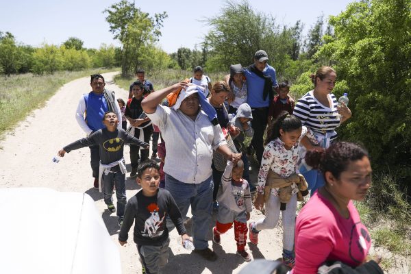 A group of illegal aliens walk up the road after crossing the Rio Grande from Mexico. Further up the road, they will board a bus bound for the Border Patrol processing facility in McAllen, Texas, on April 18, 2019. (Charlotte Cuthbertson/The Epoch Times)