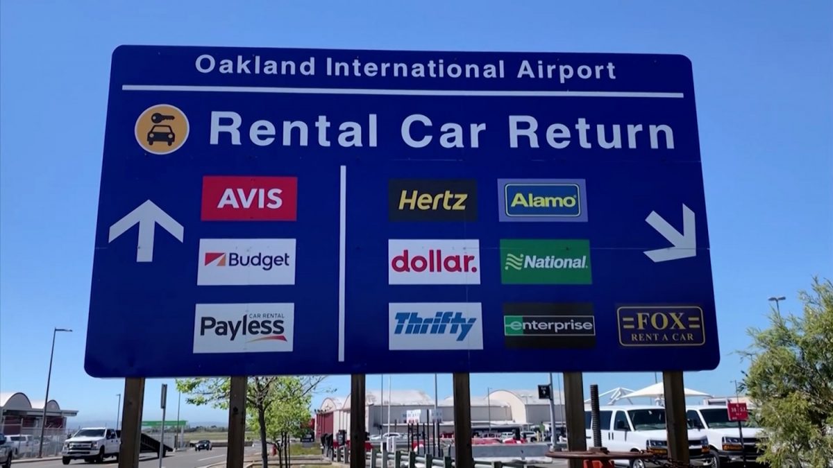 An airport road sign that gives directions to rental car locations. (Screenshot via AP)