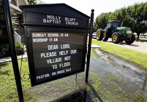 A tractor rolls past a posted prayer sign at the Holly Bluff Baptist Church calling for the small Mississippi Delta farming community to be spared from the backwater flooding, May 23, 2019. (AP Photo/Rogelio V. Solis)