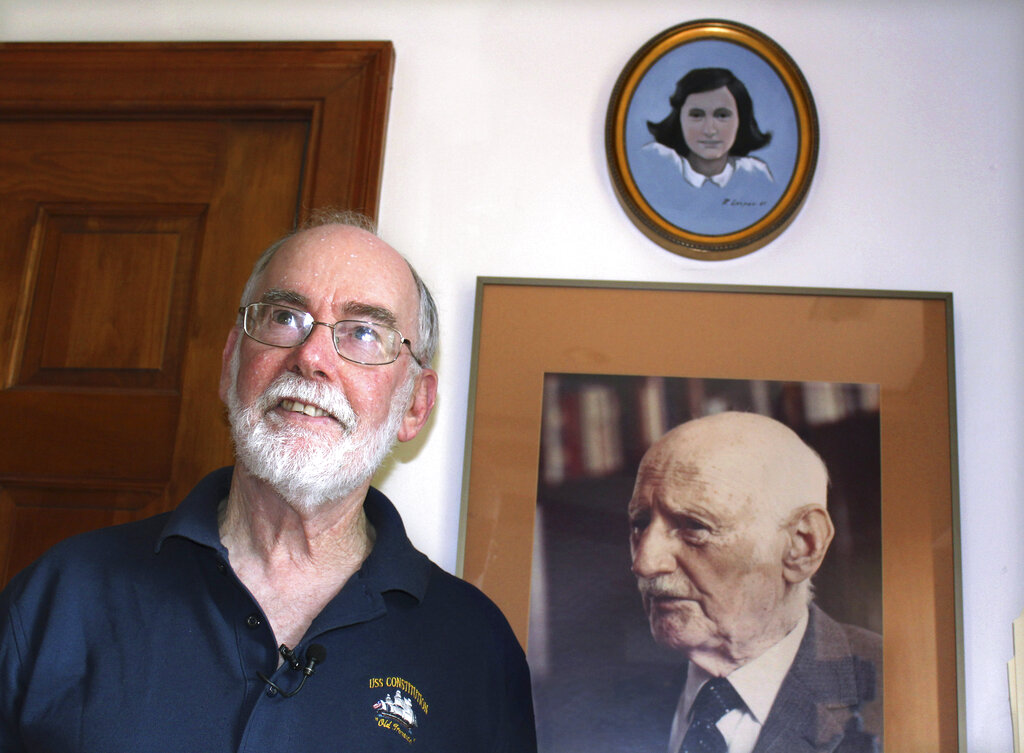 In this June 7, 2019 photo, Ryan Cooper stands next to a photo of Otto Frank, the father of the famed Holocaust victim and diarist Anne Frank, at his home in Yarmouth, Mass. Above the photo is a painting of Anne Frank by Cooper, a local artist who has donated a trove of letters and mementos he received from Otto Frank to the U.S. Holocaust Memorial Museum ahead of the 90th anniversary of Anne Frank's birthday. (Philip Marcelo/AP Photo)