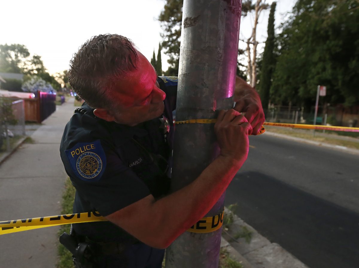 A Sacramento Police officer puts up crime scene tape near a home that authorities have surrounded where a gunman has taken refuge after shooting a Sacramento police officer, in Sacramento, Calif., on June 19, 2019. (Rich Pedroncelli/AP Photo)