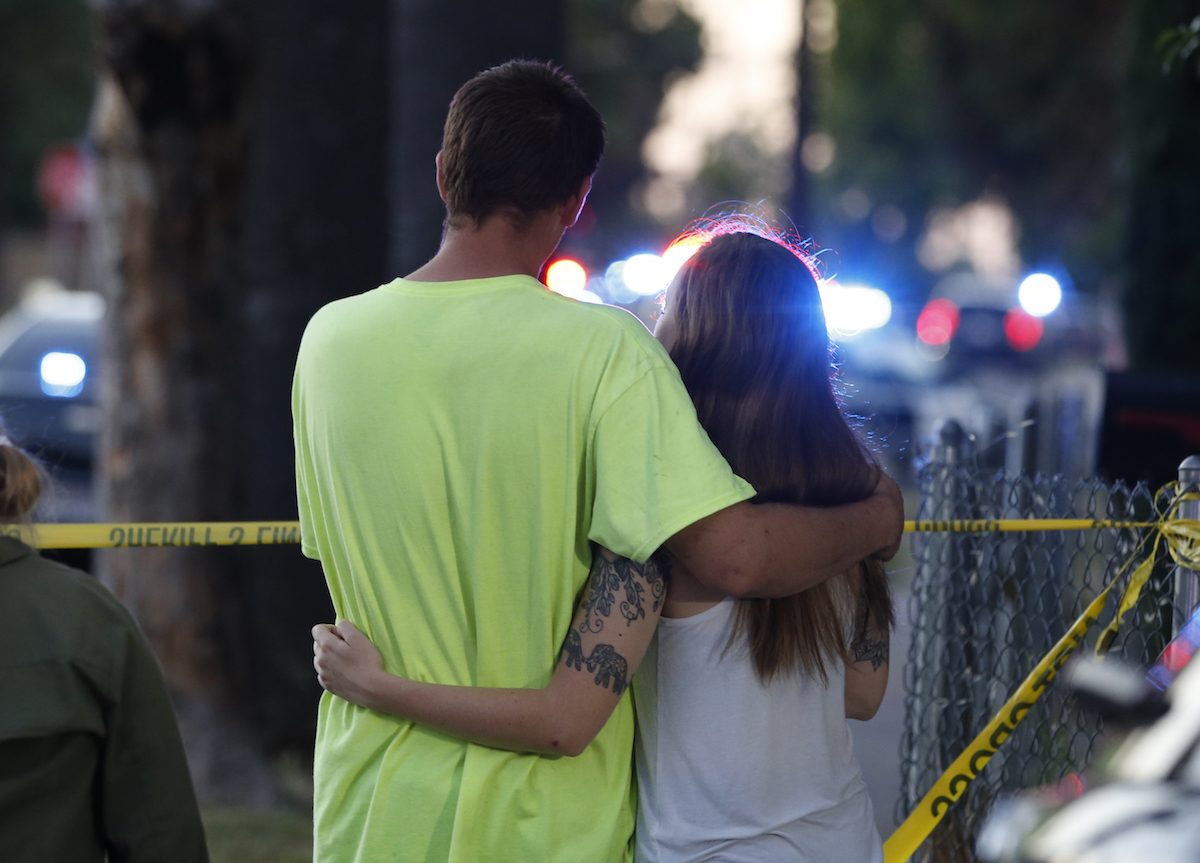 A couple stand arm in arm as they watch the activity as law enforcement officers surround a home where a rifleman has taken refuge after shooting a Sacramento police officer in Sacramento, Calif., on June 19, 2019.<br/>(Rich Pedroncelli/AP Photo)