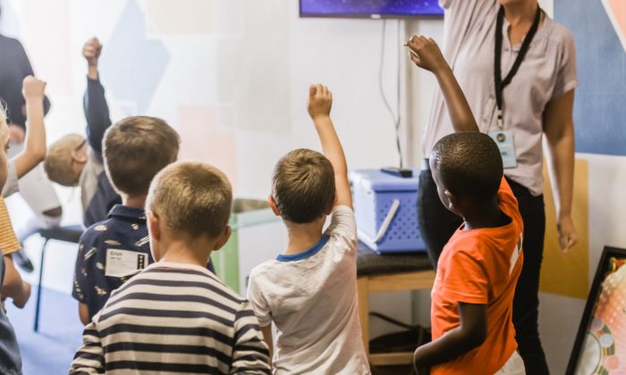 Stock photo of children raising hands in a classroom. (nicolehoneywill/Unsplash)