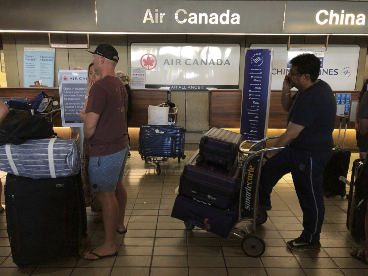 Passengers from an Australia-bound Air Canada flight diverted to Honolulu on July 11, 2019, after about 35 people were injured during turbulence, stand in line at the Air Canada counter at Daniel K. Inouye International Airport to rebook flights. (Caleb Jones/Photo AP)