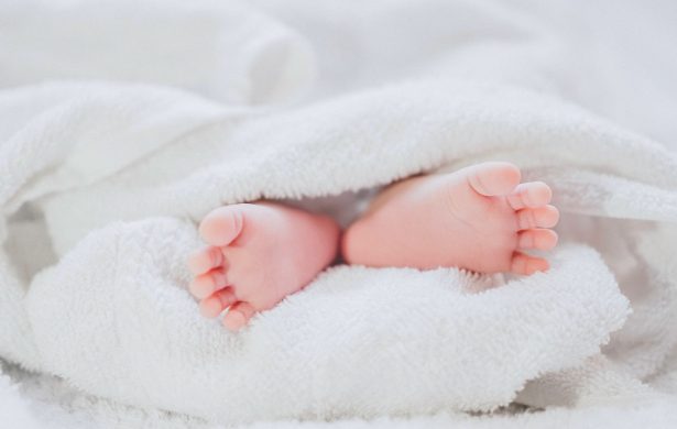 File image of a baby wrapped up inside blankets with feet poking out. (Fé Ngô/Unsplash)