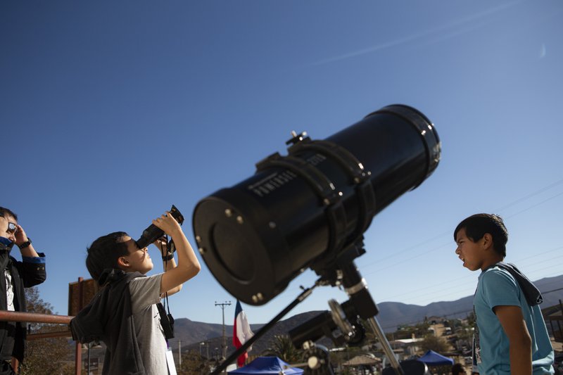 Children test out special binoculars to view tomorrow's total solar eclipse near Central Park in La Higuera, Chile on July 1, 2019. (Esteban Felix/AP)