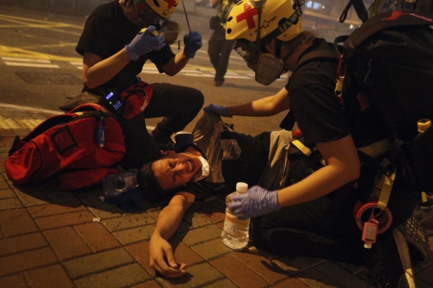 Medical workers help a protester in pain from tear gas fired by policemen