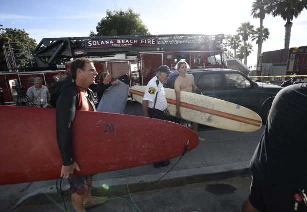 Surfers wait at the top of the stairs above the site of a cliff collapse at a popular beach in Encinitas, California, on Aug. 2, 2019. (AP Photo/Denis Poroy)